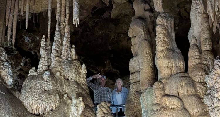 Two people inside a cave with impressive stalactites and stalagmites.