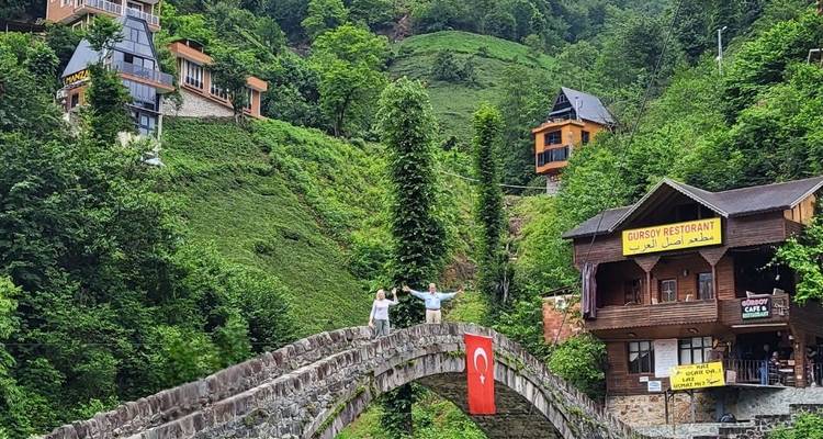 Couple posing on a historic stone bridge with scenic surroundings.