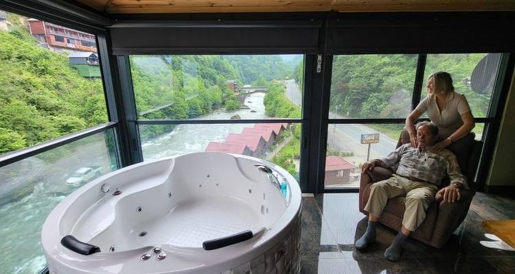 Relaxing view from inside with a hot tub and river outside.
