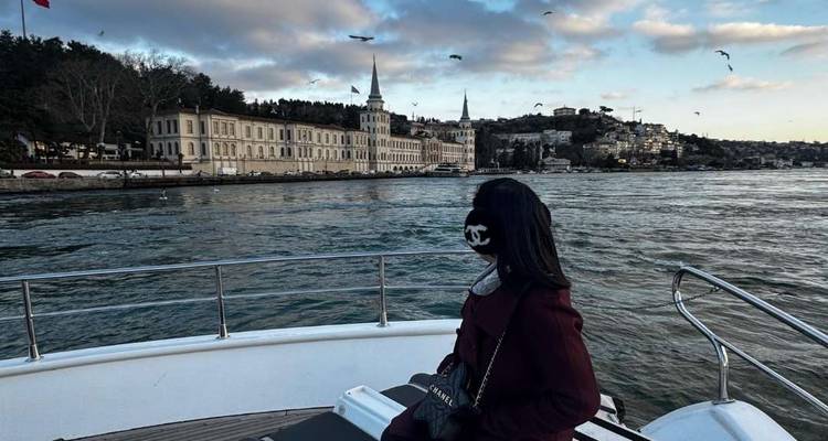 Pasajero en yate mirando hacia edificios históricos del puerto en el estrecho del Bósforo con gaviotas en el cielo