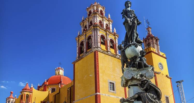 Historische kerk en standbeeld van Guanajuato tegen een heldere hemel.