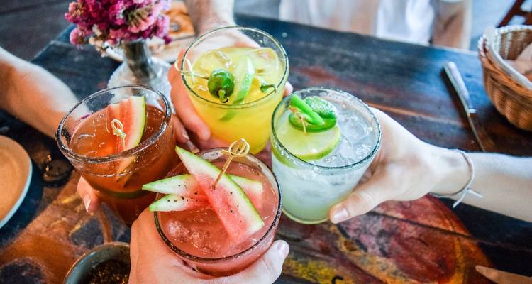 People enjoying drinks with vibrant colors on a table.