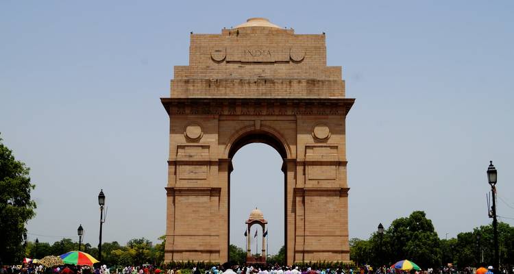 India Gate mit Besuchern und blauem Himmel.