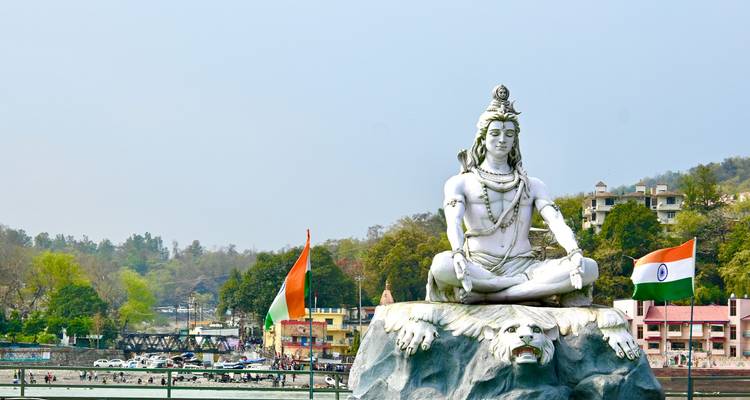 Große Statue einer Gottheit, die im Lotussitz an einem Fluss sitzt.