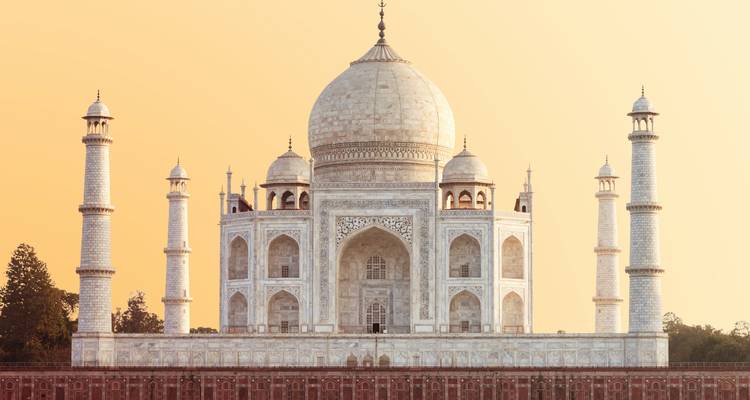Het ivoor-witte marmeren Taj Mahal staat majestueus tegen een warme dageraadhemel, perfect symmetrisch.