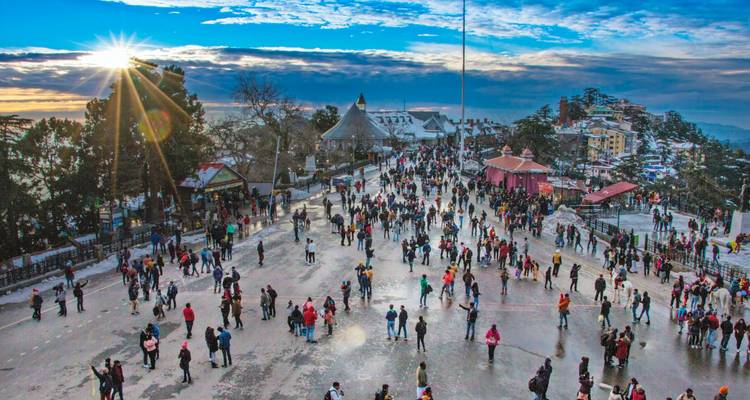 Drukke straatscène in Shimla met zonlicht en blauwe lucht.