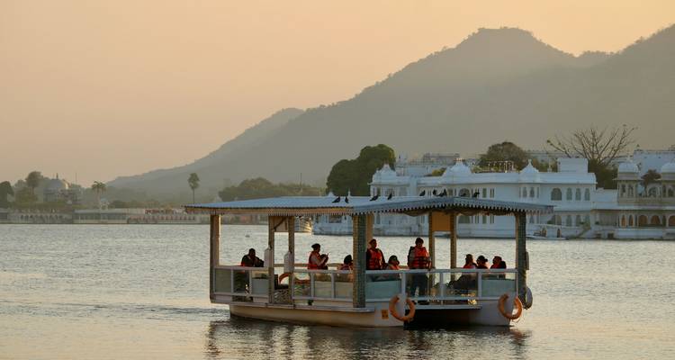 Mensen op een boot op een meer tijdens zonsondergang in Udaipur.