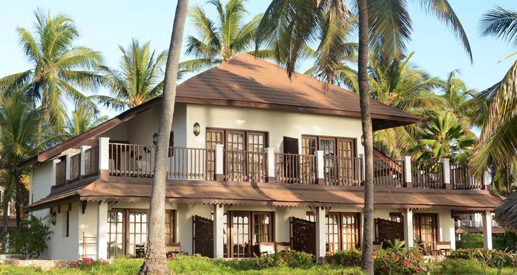 Villa à deux étages entourée de palmiers.