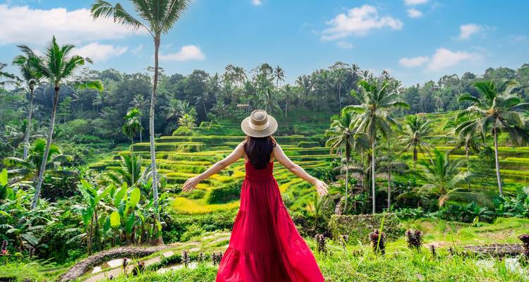 Vrouw in rode jurk die uitkijkt over rijstterrassen.