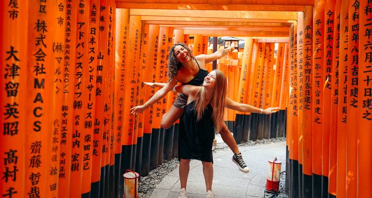 Zwei Personen posieren verspielt zwischen roten Torii-Toren.