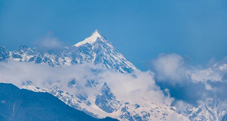 Scherpe besneeuwde bergtop met wolken.