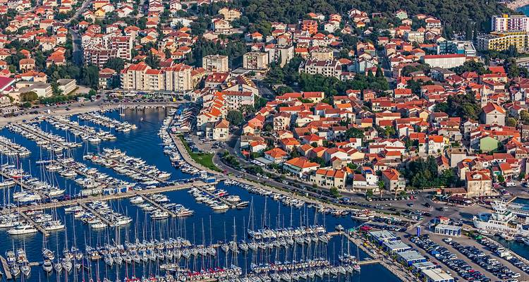 Luchtfoto van een jachthaven met veel boten en een kuststad.
