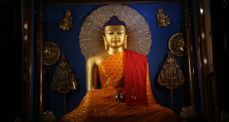 Statue von Buddha in Meditation mit Gold- und Rotdekoration.