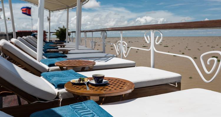 Kreuzfahrtschiff-Deck mit Liegestühlen und Blick auf den Fluss.