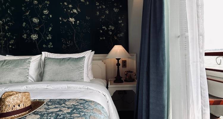 Elegantes Hotelzimmer mit einem Bett in der Nähe eines großen Fensters, dekoriert mit floralen Mustern.