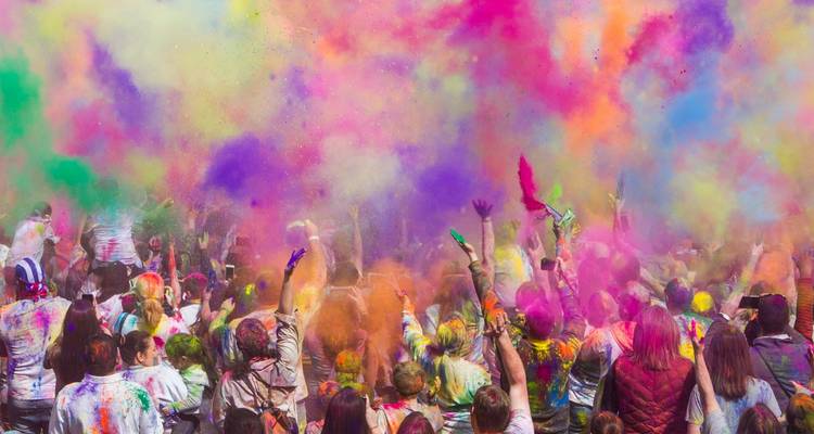 Grande foule profitant du festival de Holi avec des poudres colorées.