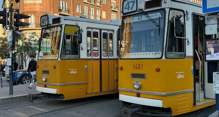 Een gele tram op een straat met gebouwen op de achtergrond.
