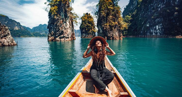 Vrouw zittend op een boot met schilderachtige kliffen rondom.