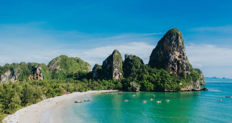Panoramisch uitzicht op een strand met groene kliffen en blauwe zee.