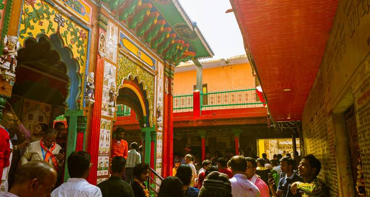 A crowded colorful temple with intricate carvings on the façade.