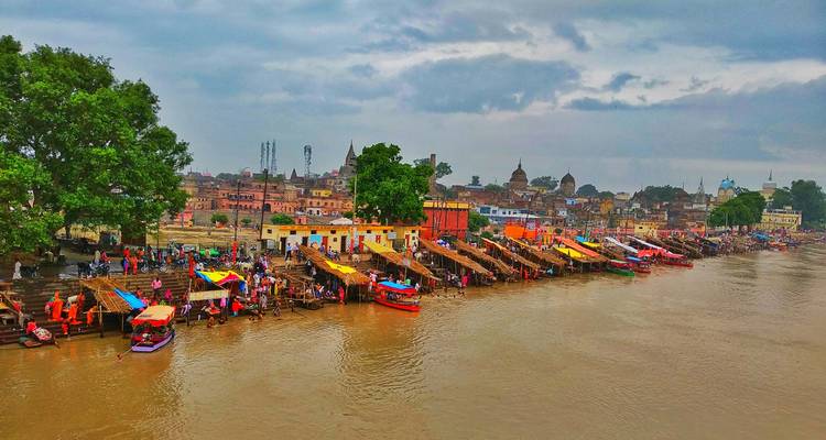 Riverbank with colorful tents and people by the water.