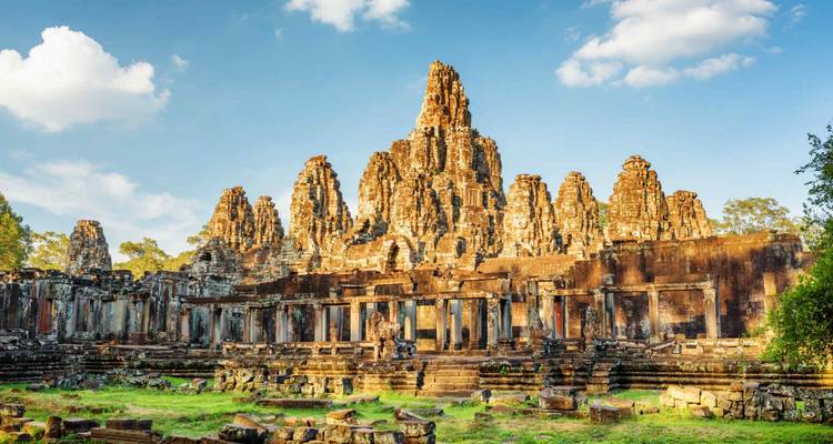 Temple du Bayon avec des visages sculptés dans la pierre sous un ciel bleu clair.