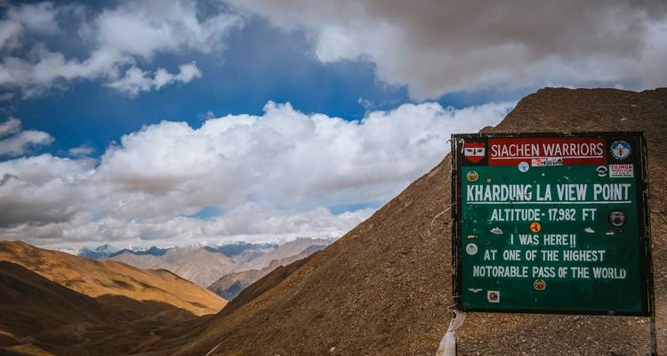 Señal de Khardung La con montañas al fondo.