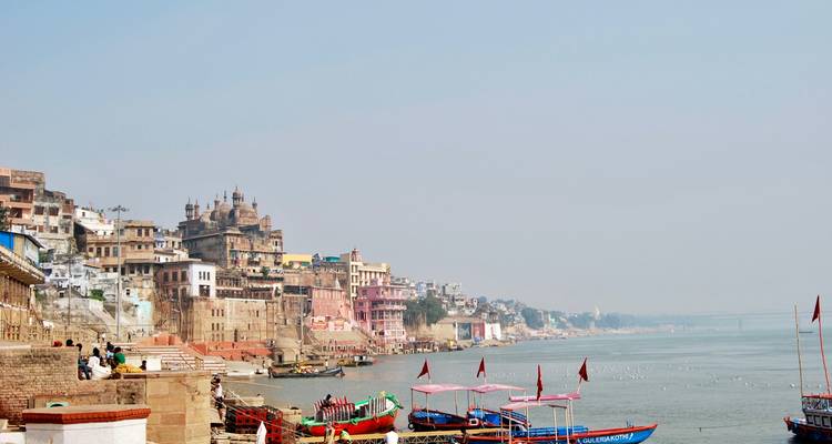Rivieroever met boten en historische gebouwen in India.