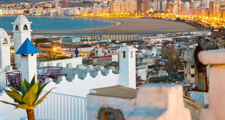 Vista de ciudad costera con edificios iluminados por la noche.