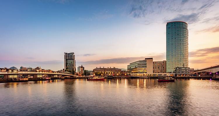 Modern skyline with a river at sunset.