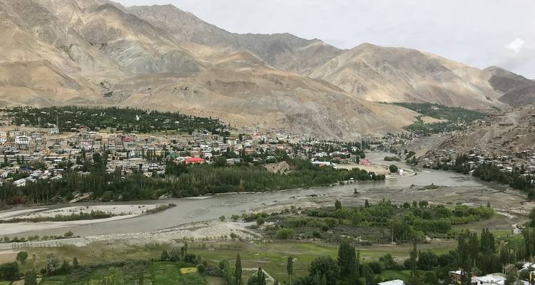 Luchtfoto van de stad Leh genesteld in de vallei met groene plekken.