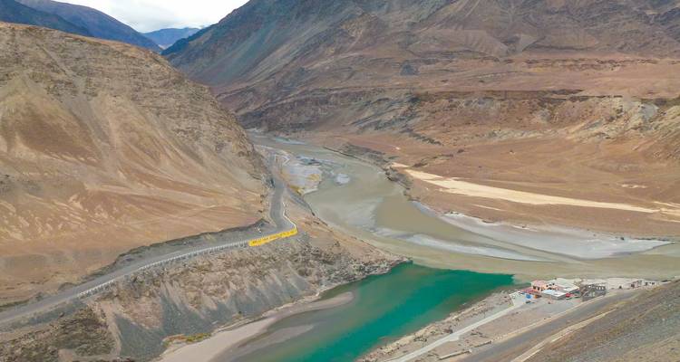 Stromende rivier door een dor landschap met omringende bergen.
