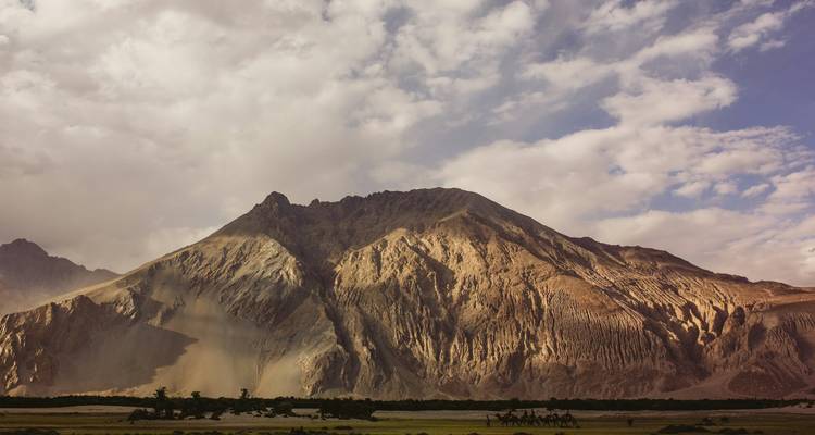 Majestieke bergen met gouden zonlicht en schaduwen, die een dramatisch landschap creëren.