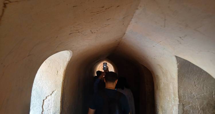 People walking through a narrow, arched passageway.