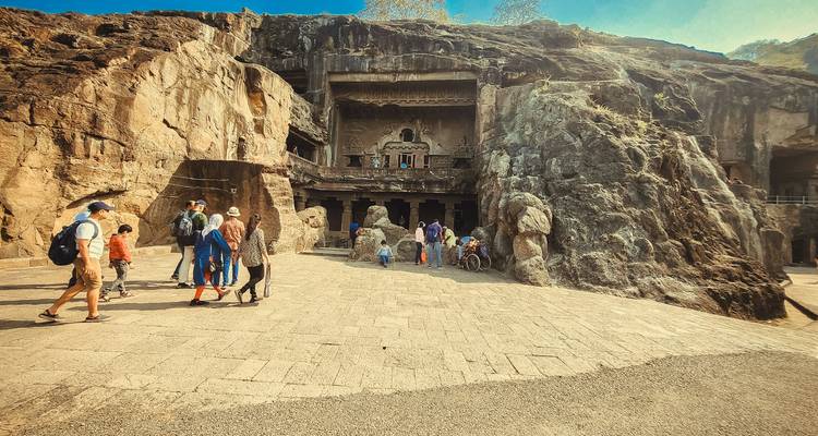 Entrée des temples-grottes taillés dans la roche avec des touristes autour.