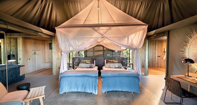 Interior of a luxurious tent with twin beds and large mosquito net.
