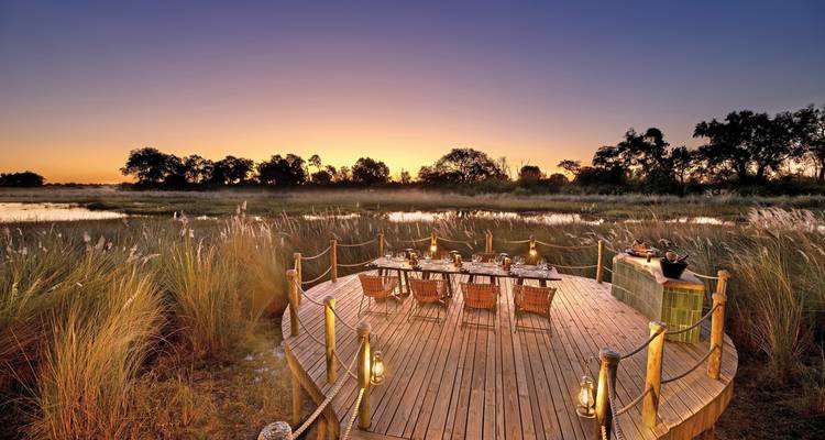 Outdoor dining setup at sunset with a view of waterside landscape.