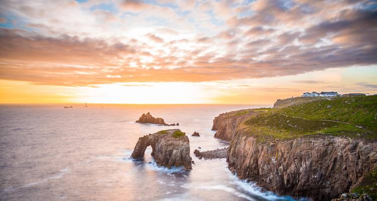 Küstenklippen mit einem natürlichen Steinbogen bei Sonnenuntergang.