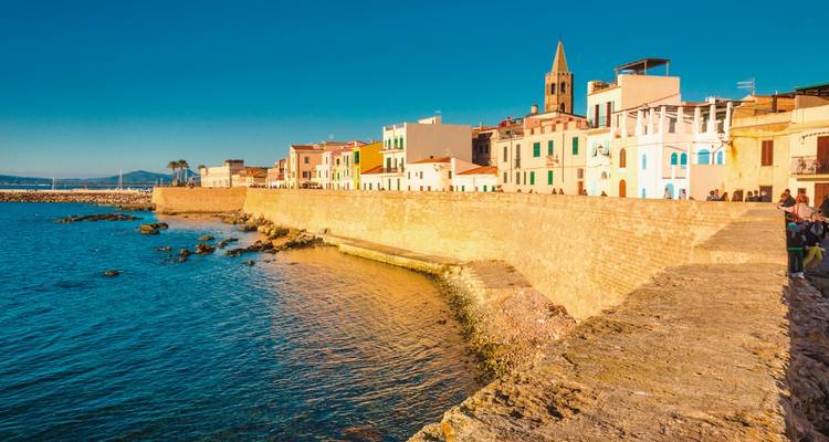 Un mur historique de la ville et des bâtiments colorés au bord de la mer.