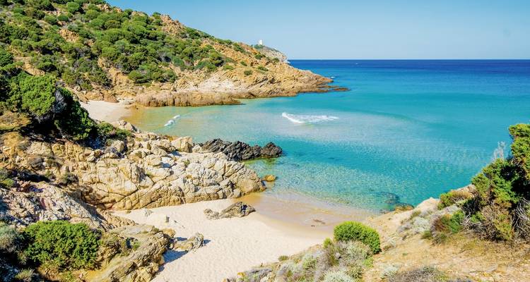 Une plage isolée avec une eau bleue claire et un environnement rocheux.