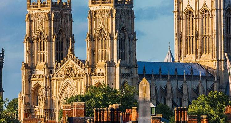 Die beiden westlichen Türme und die kunstvolle gotische Fassade des York Minster, beleuchtet von warmem Sonnenlicht.