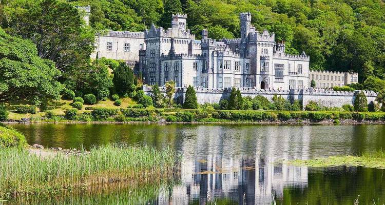 Spiegelung der historischen Kylemore Abbey in einem ruhigen Connemara-See, umgeben von üppigen Hügeln.