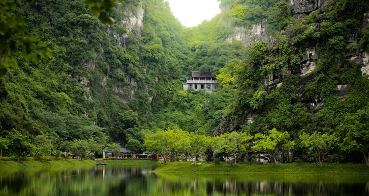 Natuurlandschap met een serene rivier en een gebouw te midden van weelderig groen.