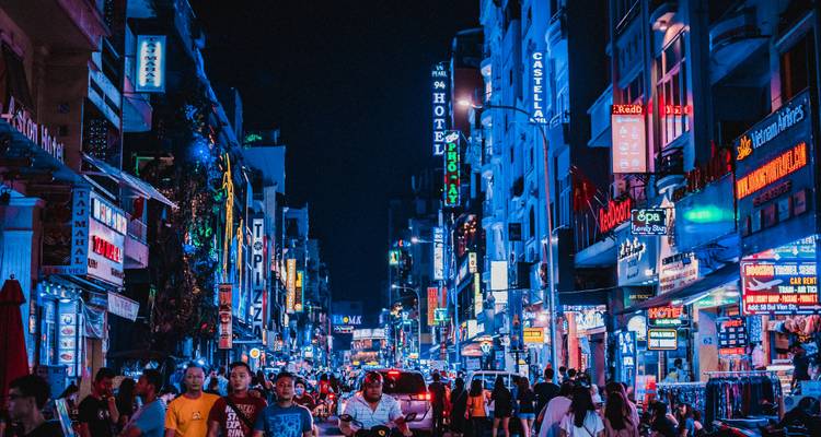 Levendige nachtscène van een drukke straat vol neonreclames.