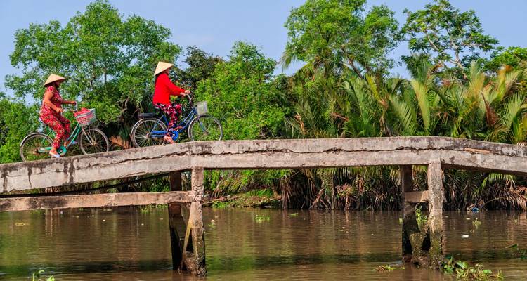 Twee mensen die fietsen op een smalle brug over een rivier.