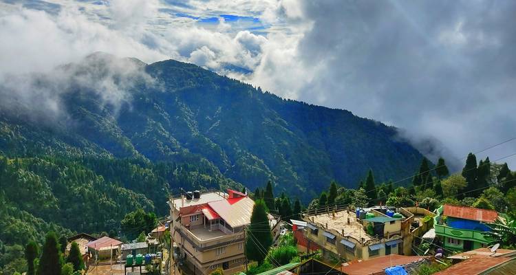 Una vista pintoresca de montaña con nubes y laderas cubiertas de árboles.
