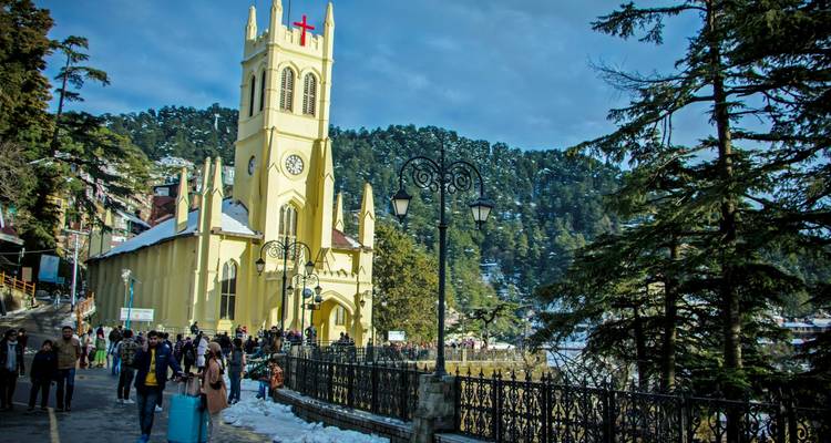 Ein Kirchturm und Menschen, die durch eine schneebedeckte Stadt gehen.