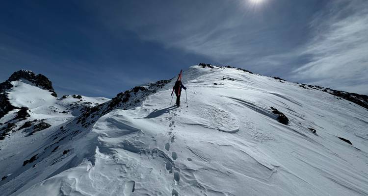 Une personne qui fait de la randonnée sur une crête de montagne enneigée.
