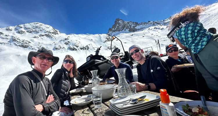 Des gens dînant en plein air avec un paysage de montagne enneigée en arrière-plan.