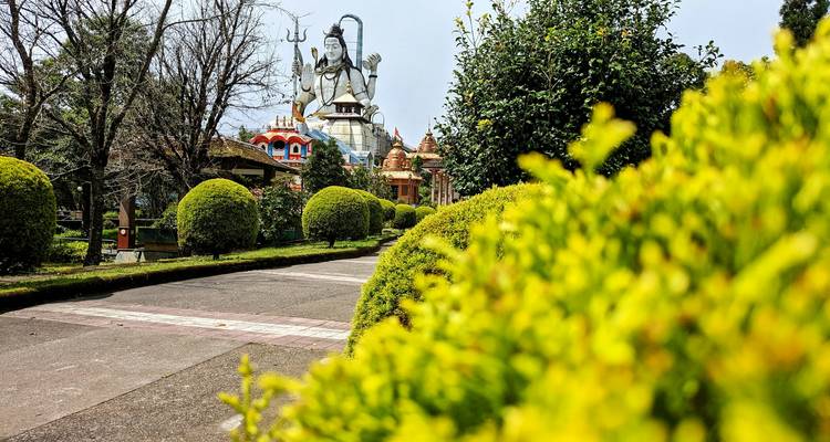Grande statue de Shiva dans un jardin bien entretenu.